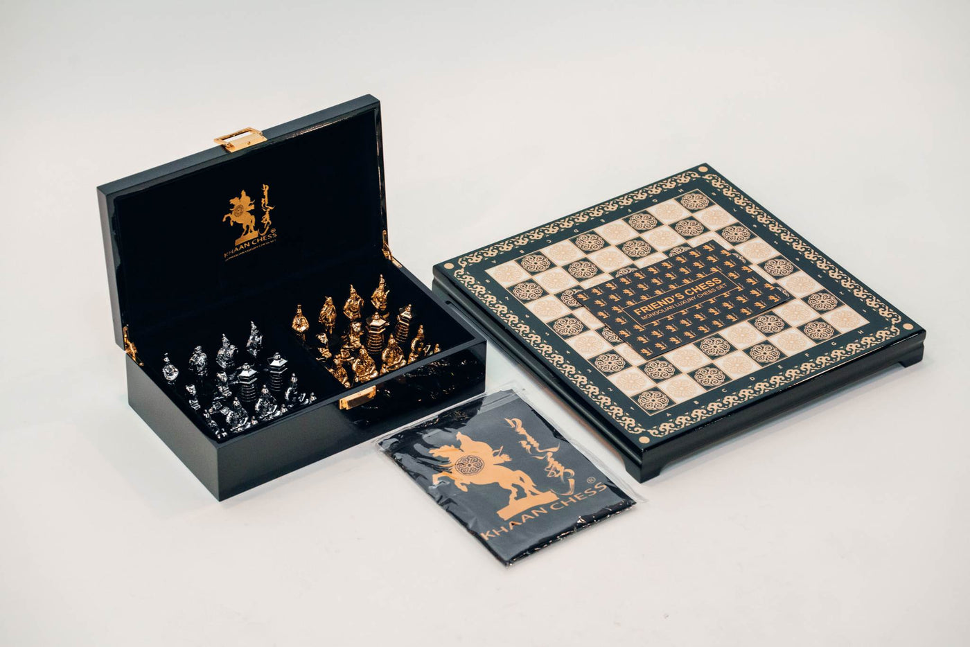 KHAN CHESS set with gold and silver chess pieces in a black case, alongside a chess board decorated with traditional Mongolian patterns