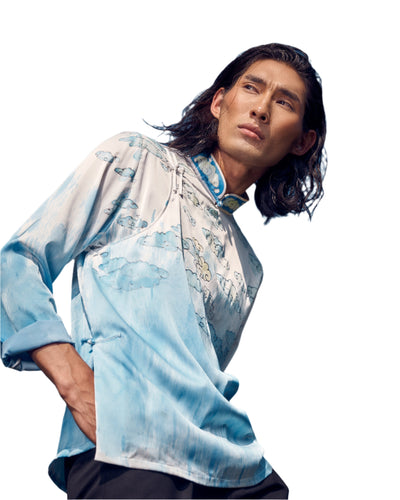 A Mongolian traditional men’s shirt crafted from silk, featuring soft blue and white tones with cloud-inspired patterns, perfect for modern elegance.