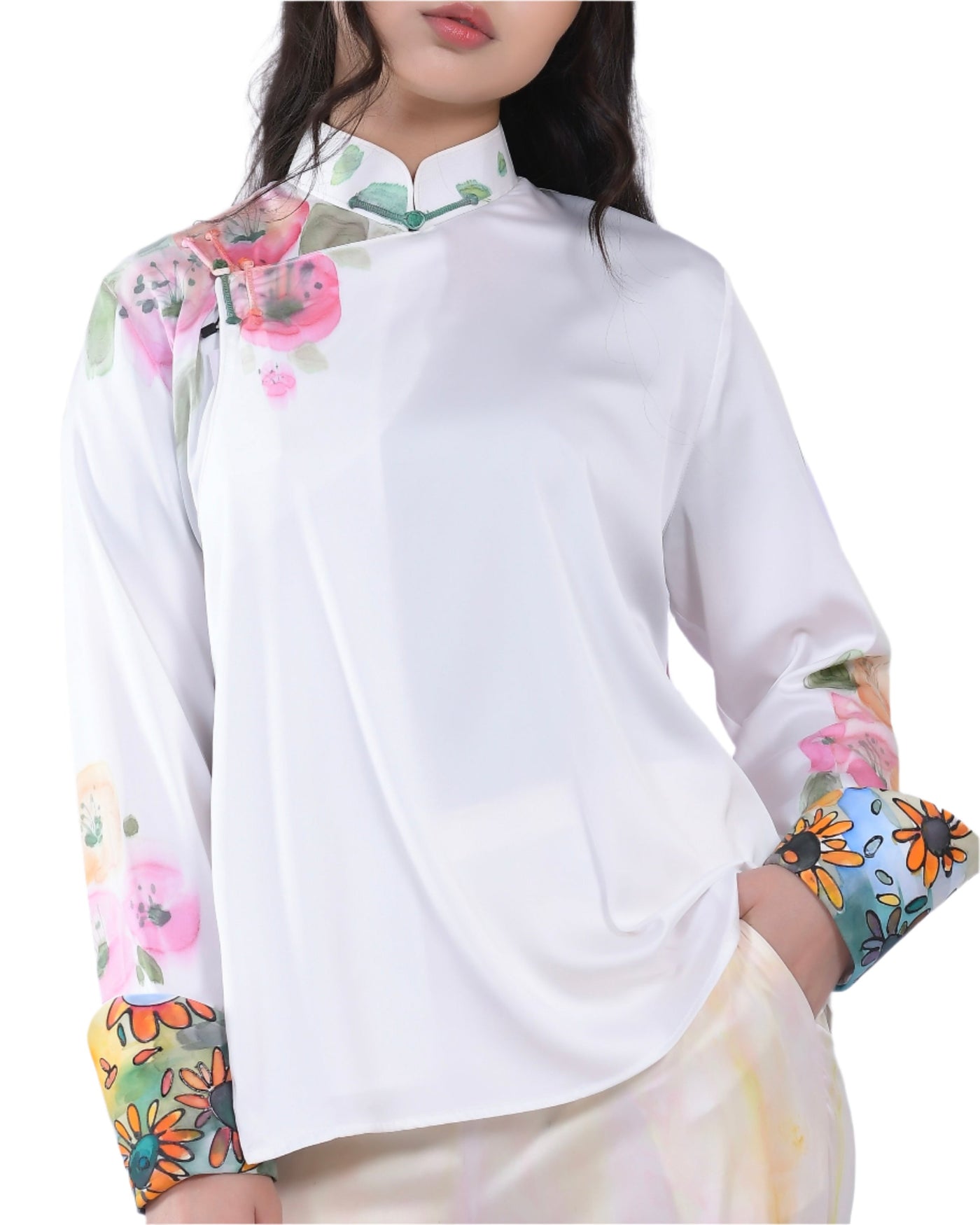 A white silk blouse with vibrant hand-painted floral designs on the shoulder and cuffs, blending artistic charm with timeless elegance.