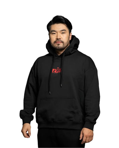 Man wearing The King Black Hoodie with a bold red logo, featuring a relaxed fit and adjustable drawstring hood for casual comfort.