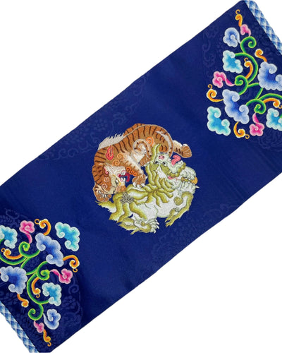 Mountains, clouds, lions, and tigers are intricately embroidered with fine threads. The edges are decorated and reinforced with a coin braid stitch on a blue silk.