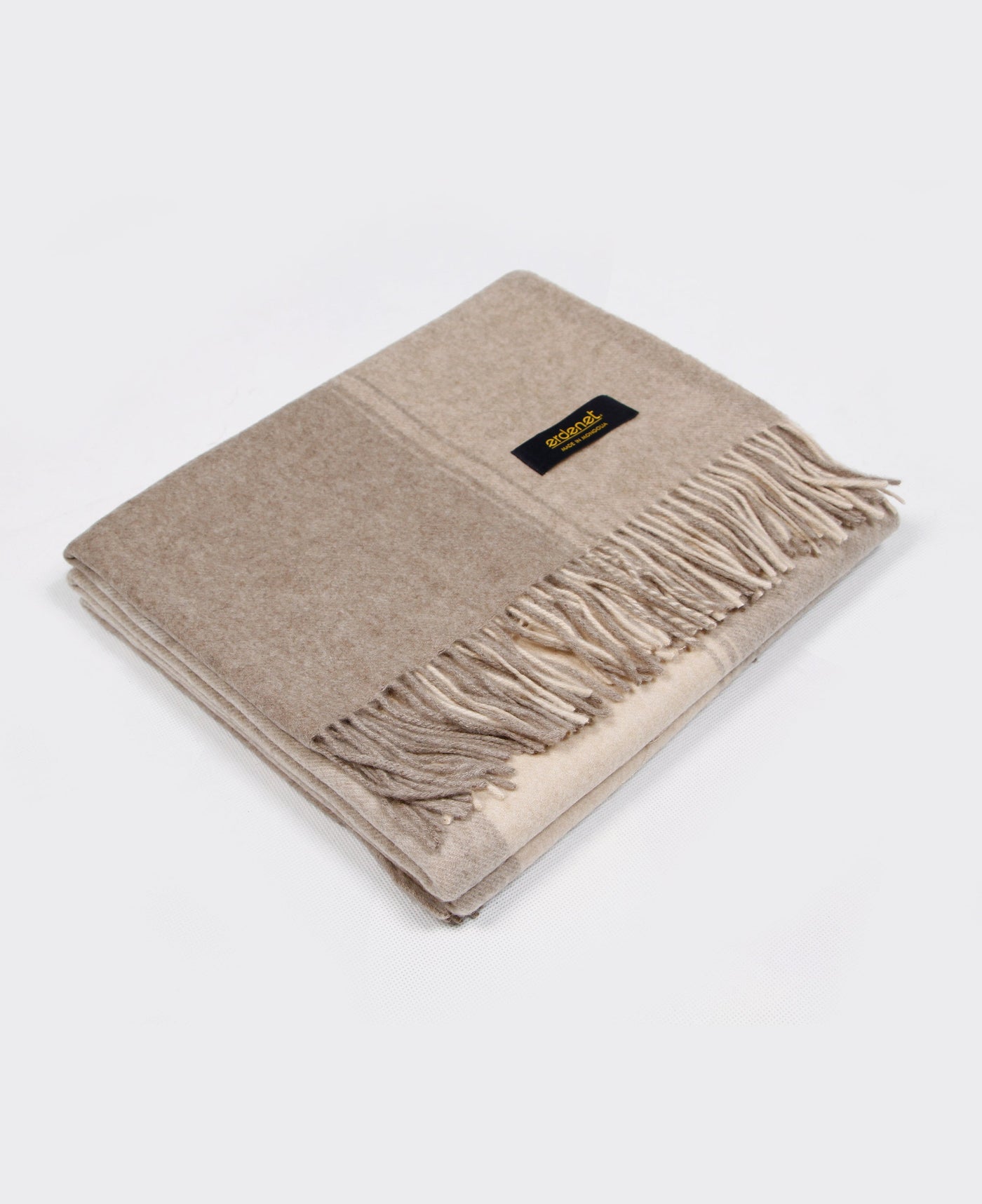 Natural beige cashmere plaid with fringed edges, sustainably sourced from Mongolia, offering luxurious warmth and elegance