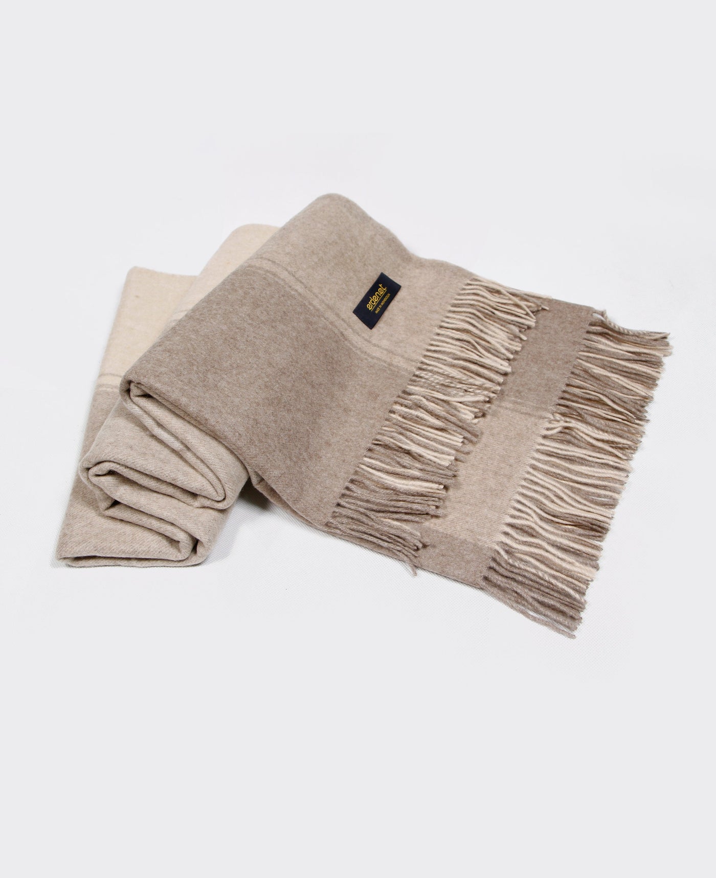 Natural beige cashmere plaid with fringed edges, sustainably sourced from Mongolia, offering luxurious warmth and elegance